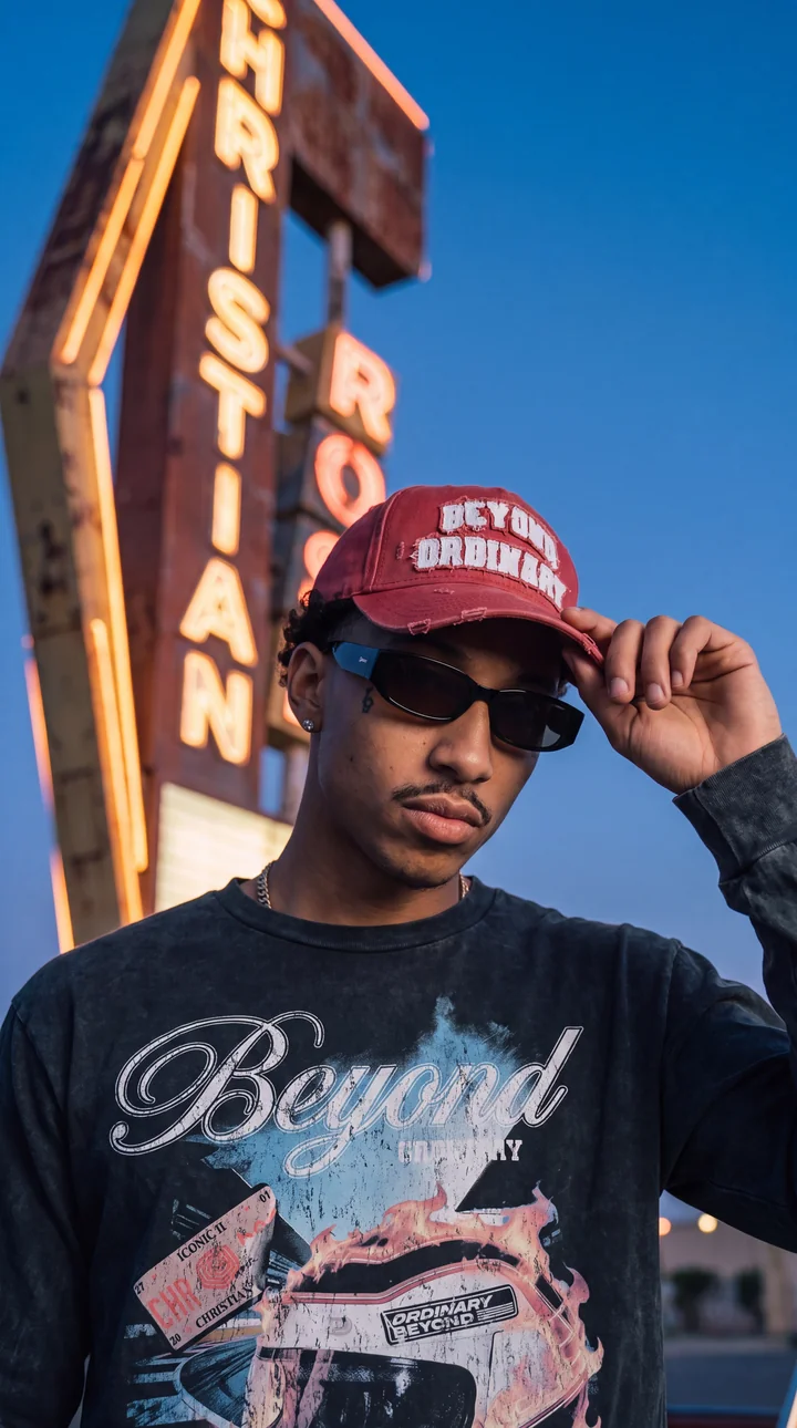 A model in a red Christian Rose cap below a roadside sign