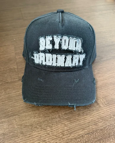 Original phone photo of the distressed Beyond Ordinary Christian Rose cap on a wooden table