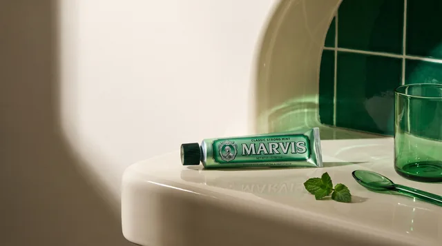 Marvis toothpaste on a sculptural ceramic washstand with green glass and mint