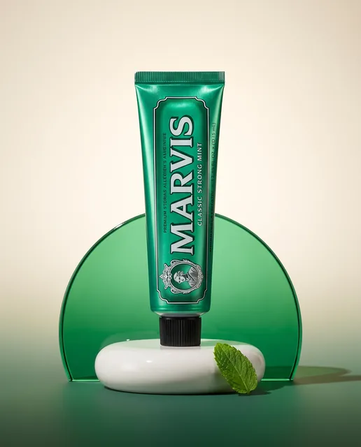A standing green Marvis tube with an emerald glass arc and white ceramic plinth