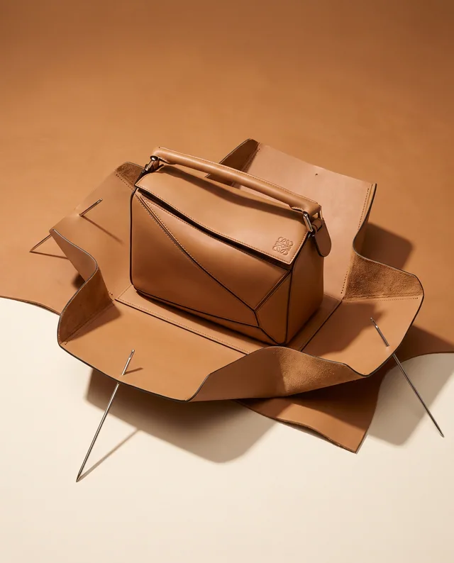 A tan LOEWE bag resting on folded leather pattern pieces
