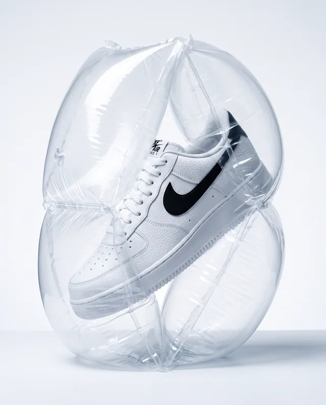 A white Nike trainer suspended inside a clear inflated air cushion